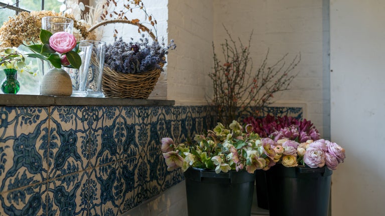 Cut flowers arranged in buckets in room with blue tiles on walls